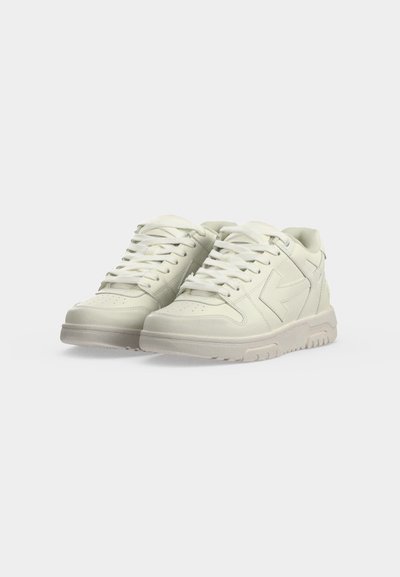 Ζευγάρι λευκά παπούτσια τύπου low-top με κορδόνια, χοντρές σόλες και λεπτές ραφές σε απλό φωτεινό φόντο.