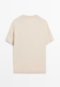 Maglietta beige a maniche corte in morbido cotone. Presenta una semplice scollatura rotonda e una texture minimalista, senza loghi o motivi visibili.