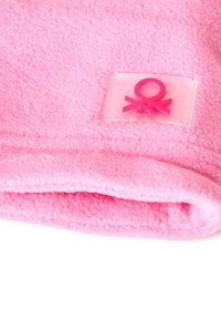 Różowy koc z polaru o teksturowanej powierzchni oraz zagiętym brzegiem. Posiada różową gumową metkę z graficznym wzorem.