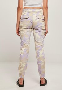 Beige camo cargo bukser med lilla accenter, med elastiske manchetter og lommer bagpå, lavet af en blød bomuldsblanding.