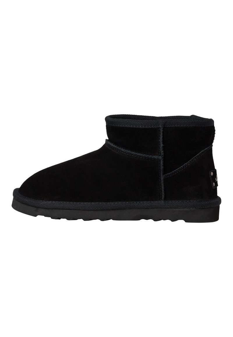 Botines de ante negro con un diseño de perfil bajo, puntera redondeada y suela de goma texturizada. Presentan una costura cosida y un detalle de marca sutil.