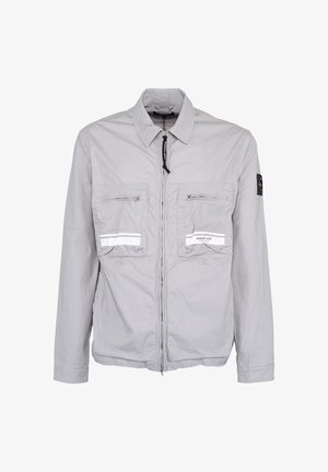 Lichtgrijze jas met rits, twee zakken met rits op de borst, reflecterende strepen en een zwarte patch op de linkermouw.