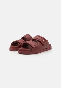 Rote synthetische Schlittensandalen mit zwei breiten Riemen, strukturiertem Obermaterial und Logo-Akzent. Flache Sohle mit leichtem Profil für Grip und Stabilität.