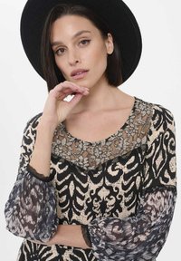 Schwarz-creamfarbenes, gemustertes Kleid mit einem Spitzenkragen, transparenten Puffärmel und strukturiertem Stoff. Mit sorgfältigen Details akzentuiert.