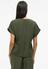 Oliven grøn kortærmet top med en afslappet pasform, rund halsudskæring og opsmøgede ærmer; glat tekstur, minimalistisk design og diskret drapering.