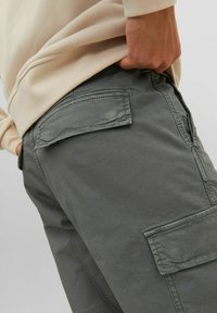 Graue Cargo-Hosen mit Seiten- und Gesäßtaschen, aus strapazierfähigem Stoff gefertigt. Die Struktur erscheint glatt, mit sichtbaren Nähten.