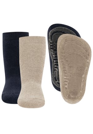 Zwei Paar Socken, ein marineblaues und ein beiges, beide mit rutschfesten Gummigreifen auf der Sohle, nebeneinander angeordnet.