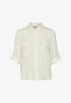 Svijetlo krema bluzica kratkih rukava izrađena od mekog materijala. Sadrži prednji dio na gumbe, dva džepa na prsima i smotane rukave.