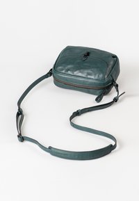 Borsa a tracolla in pelle teal con forma rettangolare, chiusura con zip e tracolla regolabile. Texture liscia con minimi dettagli in metallo.