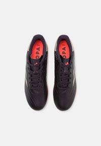 Black soccer shoes with a smooth finish, featuring a contrasting bright coral insole, textured rubber outsole, and grey accents.