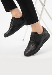 Sneaker nere con pannelli in pelle liscia e rete, design con lacci e suole in gomma. Lo stile presenta un profilo basso e un tallone ammortizzato.