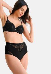 Ensemble de lingerie noire comprenant un soutien-gorge rembourré avec un revêtement en dentelle et une culotte taille haute avec des détails en dentelle. Tissu lisse avec un léger éclat.