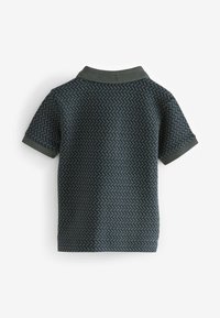 Polo a maniche corte di colore verde scuro con una texture a zigzag, dotato di colletto e polsini a costine. Tessuto liscio.