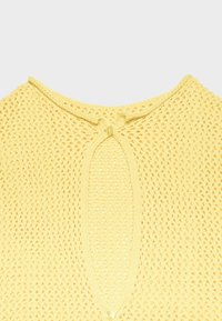 Gelb gestricktes Kleidungsstück mit Lochmuster, mit einem Schlüsselloch-Ausschnitt, der mit zwei kleinen Knöpfen gesichert ist.