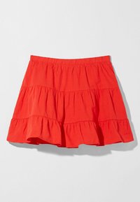 Gonna mini a strati rossa con vita elastica e dettagli in tessuto arricciato su uno sfondo chiaro e semplice.