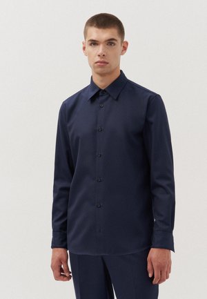 Marineblauwe langemouwshirt van een gladde stof, met een knoopsluiting aan de voorkant, puntige kraag en een relaxte pasvorm.
