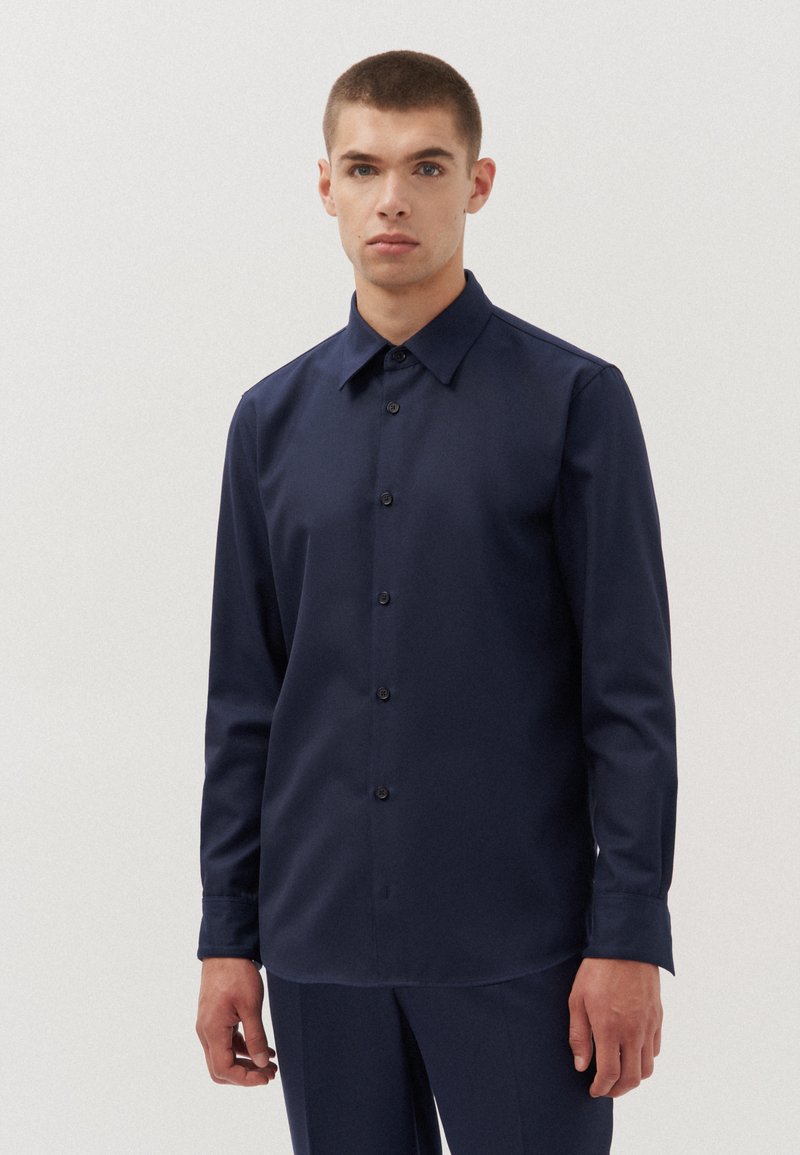 Camicia blu navy a maniche lunghe in un tessuto liscio, con chiusura a bottoni, colletto a punta e vestibilità comoda.