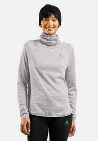 Lichtgrijze langemouwtop met een cowl neck, gemaakt van textuurstof. Logo op de borst, gecombineerd met zwarte leggings met een logo.