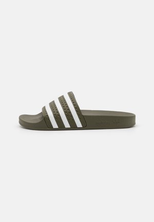 Olijfgroene Adidas slippers met een witte band met drie strepen en een gestructureerd voetbed, zijaanzicht, op een lichtgrijze achtergrond.