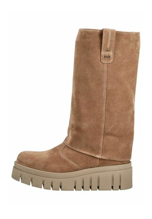 Heller Wildleder-Stiefel bis zur Mitte der Wade mit dicker, beiger, klobiger Sohle und Zuglasche mit kleinem Metalllogo an der Seite.