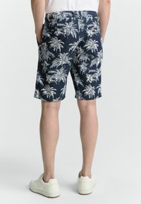 Marineblaue Shorts mit einem weißen Palmenmuster, aus leichtem Stoff gefertigt, mit seitlichen Taschen und einem lässigen Schnitt.