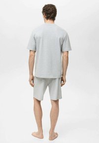 Grå bomulds-T-shirt med korte ærmer og matchende shorts. Enkel design, afslappet pasform og glat tekstur. Ingen synlige mønstre eller accenter.