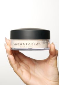 Transluzente lose Puderdose mit einem schwarzen Deckel, transparentem Boden und beigem Puder darin. Das Etikett trägt die Aufschrift "Anastasia Beverly Hills."