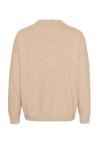 Beez värvi kootud sviiter laia siluetti, V-kujulise kaelusega, laiade varrukatega ja peene täpikeste tekstuuriga. Tagantvaadet nähes on näha ühtlane värv ja minimaalne detail.