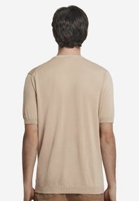 Beige kortærmet skjorte lavet af glat stof, med rund hals og ribbede manchetter, samt et ensfarvet rygdesign.