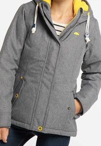 Grå isolerad jacka med foder i gul huva, två sidofickor, gula detaljer, justerbara snören och en diskret logotyp.