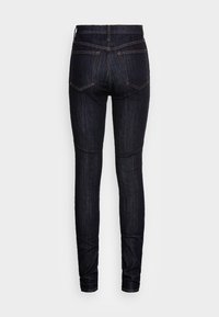 Jeans skinny de denim oscuro con cintura alta, que presentan un clásico diseño de cinco bolsillos y costuras en contraste a lo largo de las costuras.