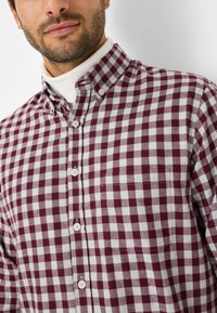 Camicia button-up a quadretti con un motivo bordeaux e bianco, colletto classico e pattina frontale con bottoni bianchi. Tessuto in cotone.