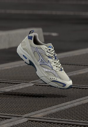Light gray athletic sneaker with blue accents, mesh upper, rounded toe, and cushioned sole. Features lace-up design and logo detail.