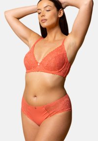 Soutien-gorge en dentelle corail avec des bretelles réglables et un bord festonné, associé à des culottes corail avec des accents en dentelle sur les côtés.