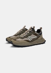 Olivgrüne Sportschuhe mit sandfarbigen Akzenten, strukturierten Überzügen und schwarzen Gummisohlen, die ein gemustertes Profil für besseren Grip aufweisen.
