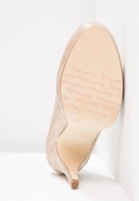 Chaussure à talon haut beige avec dessus texturé, bout pointu et talon fin en forme d'épingle. Semelle lisse, légèrement brillante avec l'empreinte de la marque.
