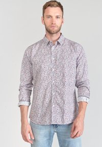 Camicia a maniche lunghe con bottoni, realizzata in tessuto bianco con un motivo floreale in tonalità di rosso e blu, con un polsino a motivo contrastante.