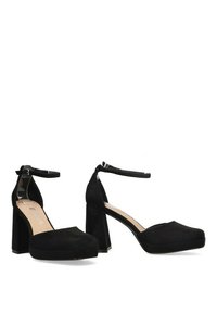 Zapatos de tacón alto de ante negro con plataforma, correa en el tobillo y tacón cuadrado. Presentan una textura suave y un diseño de punta redondeada.