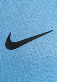 Odzież Nike w kolorze jasnoniebieskim, wykonana z gładkiego materiału, z wyraźnym czarnym logo Swoosh. Tekstura jest tkaninowa i oddychająca.