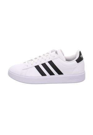 Zapatilla blanca de Adidas con tres franjas negras en el lateral, cordones blancos y lengüeta trasera negra con el logo de Adidas.