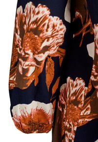 Tkanina s květinovým vzorem v námořnické modři, s velkými oranžovými a smetanovými květinami. Textil má měkkou strukturu a na manžetě je nařasený elastický pás.