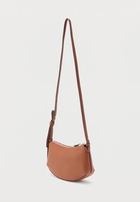 Καφέ δερμάτινη τσάντα χιαστί με ρυθμιζόμενο λουρί και κλείσιμο με φερμουάρ, εμφανιζόμενη κρεμασμένη σε απλό λευκό φόντο.