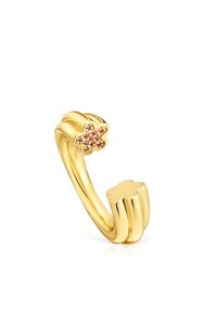 Anillo de metal dorado con un diseño de banda retorcida, que presenta una pequeña flor con piedras preciosas en tonos rosa y amarillo. Textura suave con acabado pulido.