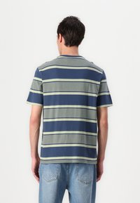 Lühikeste varrukatega tumesinine puuvillane T-särk, roheliste ja valgete horisontaalsete triipudega, mugav lõige, ümarkaelus ja sirge äär.