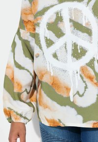 Felpa in cotone con un motivo tie-dye verde, arancione e bianco, dotata di un grande simbolo di pace bianco e lievi decorazioni.