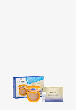 Shiseido hudplejesæt med solmakeup-kompakt, SPF 50+ creme tube og Vital Perfection øjenmaske-pakke mod hvid baggrund.