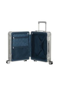 Valigia rigida con finitura argento. L'interno presenta un tessuto blu scuro, fodera decorata, tasche in rete e cinghie incrociate per un imballaggio sicuro.