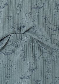 Blue ribbed fabric with line drawings of polar bears, whales, and penguins in dark blue, showing gathered elastic detail.