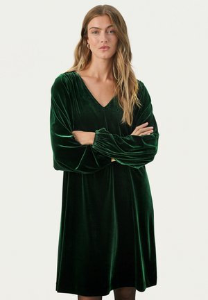 Abito verde in velluto con scollatura a V, lunghe maniche a sbuffo e silhouette a campana, caratterizzato da una morbida texture e un aspetto lussuoso.