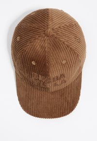 Gorra de pana marrón con logo bordado. Presenta una corona redondeada, textura acanalada y agujeros de ventilación. Visera curva con costura plana.
